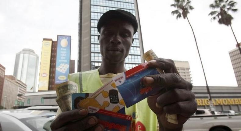 Qualified carpenter Alex Mhazo sells mobile phone cards in central Harare, in this picture taken April 1, 2014. REUTERS/Philimon Bulawayo