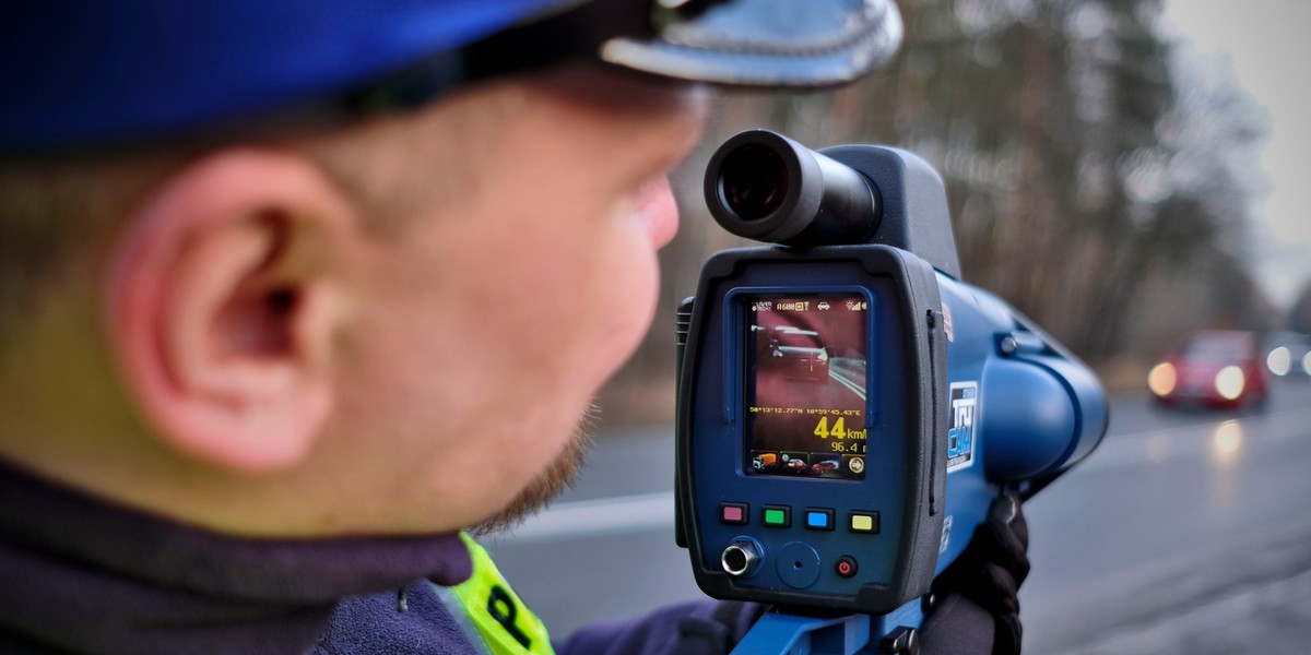 Policjant dokuje pomiaru prędkości laserowym miernikiem.