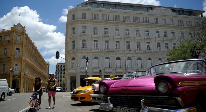 Cubans walk near the Manzana Kempinski Hotel, the first ultra luxury hotel in Cuba, on May 22, 2017
