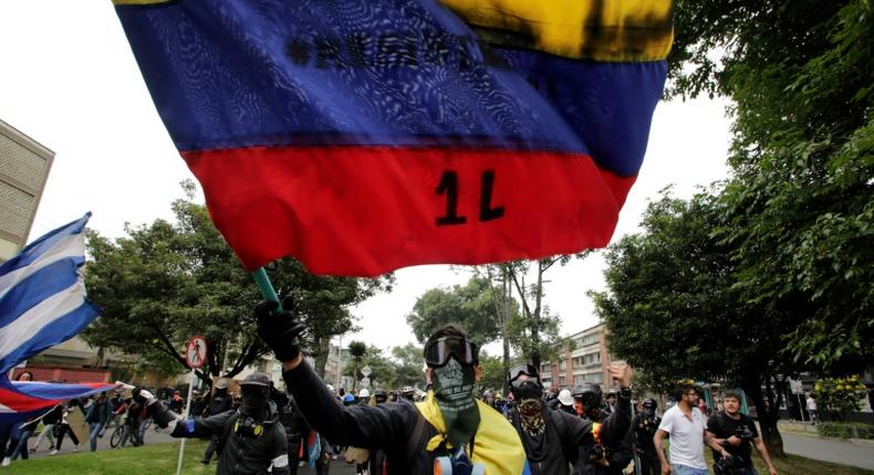 Protestors with their faces covered wave flags during a demonstration against the government of Colombia’s President Ivan Duque in Bogota