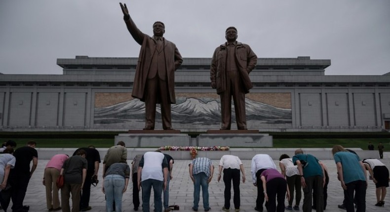 Tourists bow before statues of late North Korean leaders Kim Il-Sung (L) and Kim Jong-Il (R), on Mansu hill