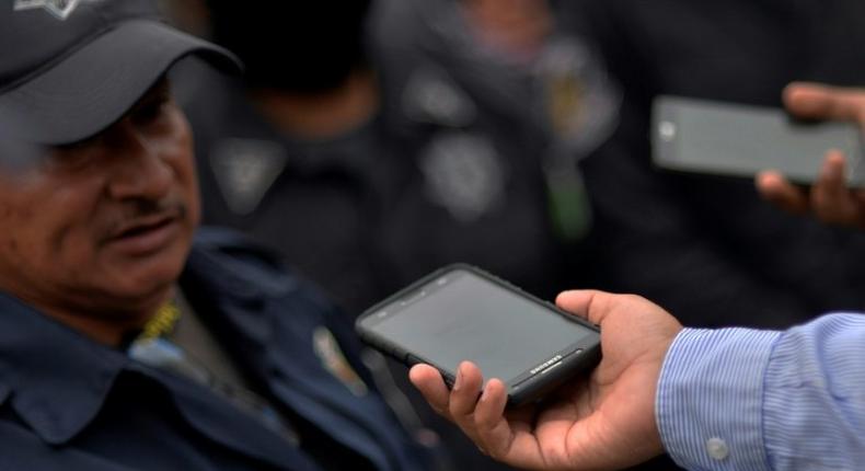 A Mexican journalist interviews a police officer during a protest rally in Chilpancingo, Guerrero state