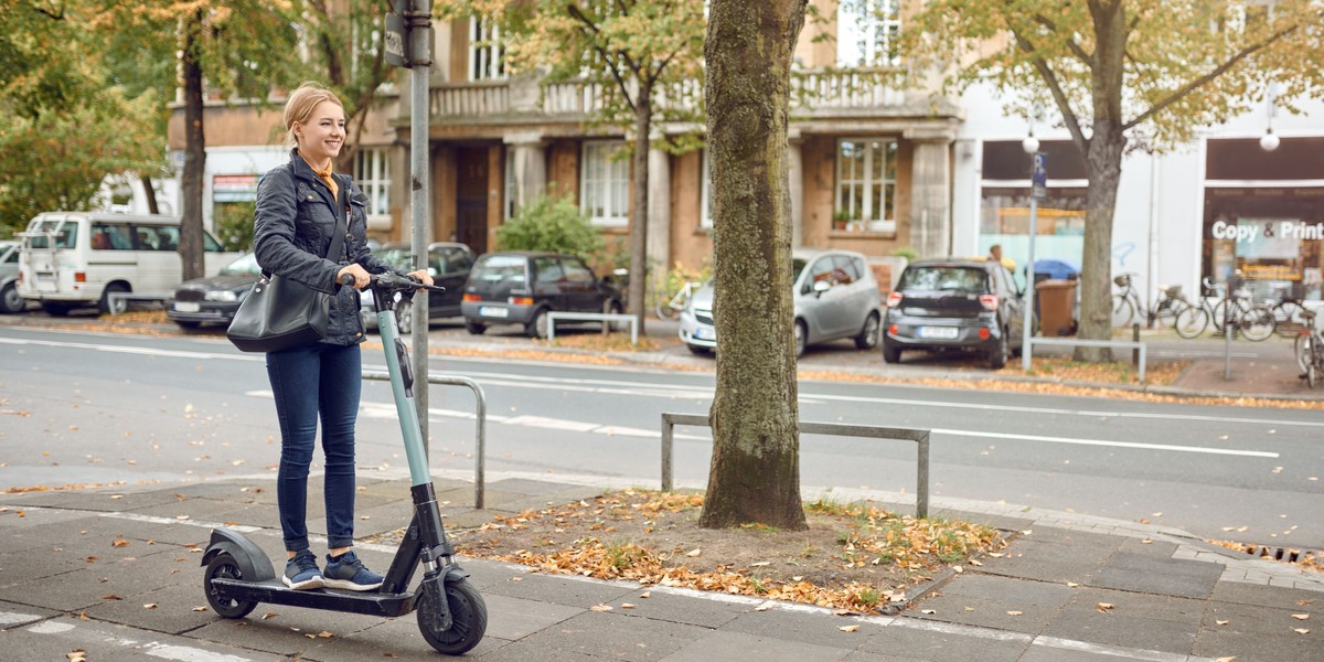 Young happy woman riding an electric scooter in the city