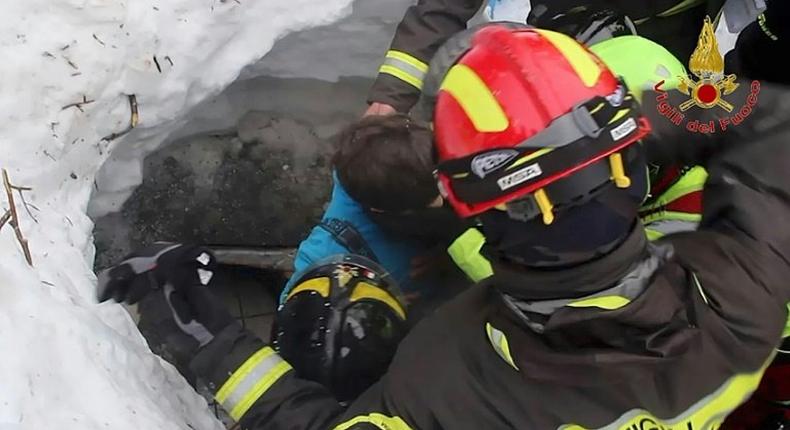 Picture released by Italy's Vigili del Fuoco fire service shows a child (C) being rescued from the Hotel Rigopiano, in the mountains of central Italy, on January 20, 2017 after they were buried under an avalanche