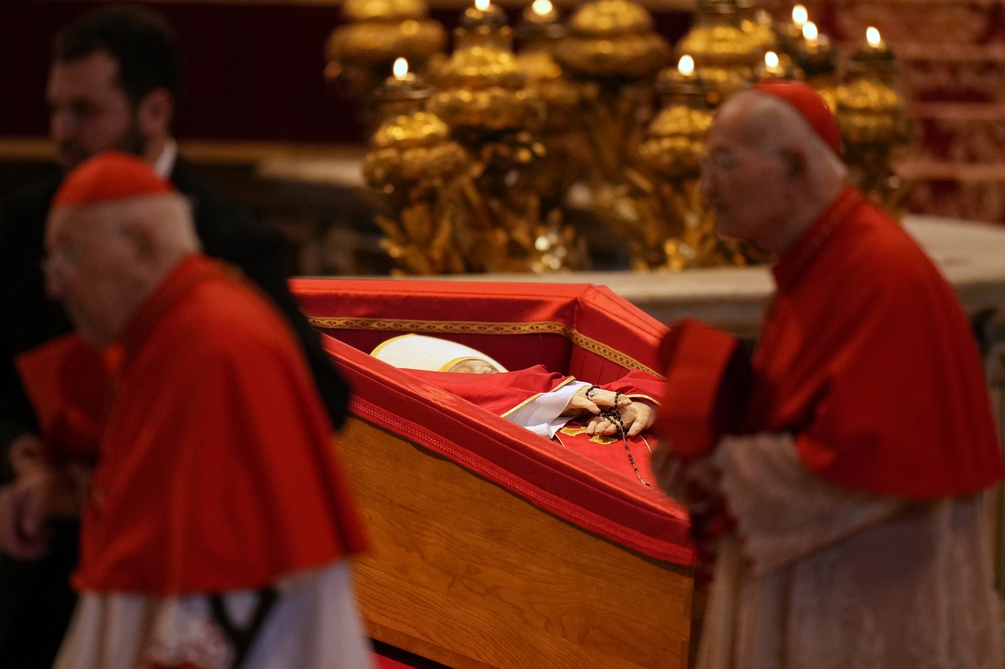 Kardináli kráčajú okolo vystavenej rakvy s telom zosnulého pápeža Františka v Bazilike sv. Petra vo Vatikáne.