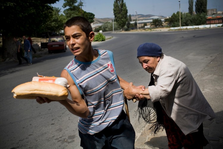 Gruziński chłopiec niosący chleb wyprowadza kobietę z Tskhinvali, ok. 80 km od Gori, 11 sierpnia 2008
