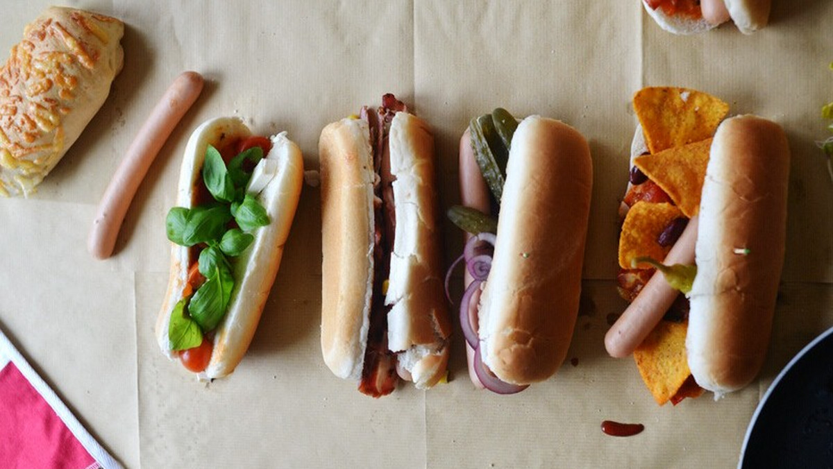 Domowe hot-dogi są super na kolację zwłaszcza, jeśli przyrządzone z dużą ilością warzyw, wypieczoną bagietką i dobrej jakości parówką. Bardzo przypominają kanapkę na ciepło, którą z powodzeniem można wziąć sobie do pracy. Ta potrawa doskonale nadaje się do przygotowania z dziećmi, a także na dziecięce przyjęcia. Przede wszystkim jest prosta i szybka do zrobienia! Podobno fast foody są niezdrowe, ale wcale nie muszą... wystarczy dobrać odpowiednie składniki. Zosia Cudny poleca kilka przepisów na smaczne, domowe hot dogi!