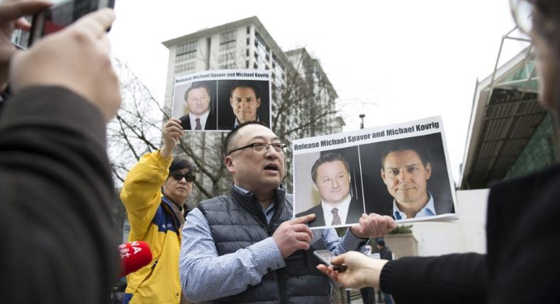 Louis Huang of Vancouver Freedom and Democracy for China holds photos of Michael Spavor and Michael Kovrig who have now spent a year in Chinese detention