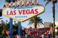 People sign a banner near the Welcome to Fabulous Las Vegas sign following the Route 91 music fest