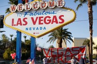 People sign a banner near the Welcome to Fabulous Las Vegas sign following the Route 91 music fest