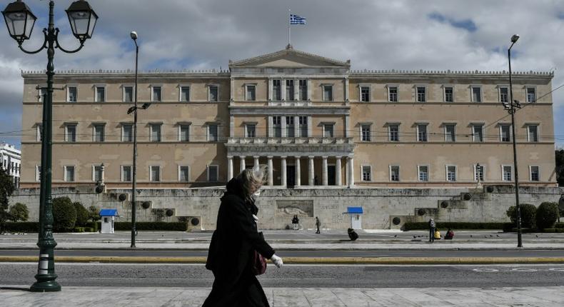 A woman wearing a face mask walks past the empty Syntagma Square in Athens, in front of the Greek Parliament early during the outbreak of COVID-91.