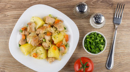 Chicken meat with potatoes, carrot and onion, bowls with scallion