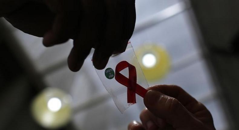 A nurse (L) hands out a red ribbon to a woman, to mark World Aids Day, at the entrance of Emilio Ribas Hospital, in Sao Paulo December 1, 2014. REUTERS/Nacho Doce