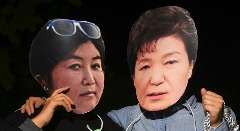 Protesters wearing masks of South Korean President Park Geun-Hye (R) and her confidante Choi Soon-Sil pose for a photo during a rally in Seoul, on October 27, 2016