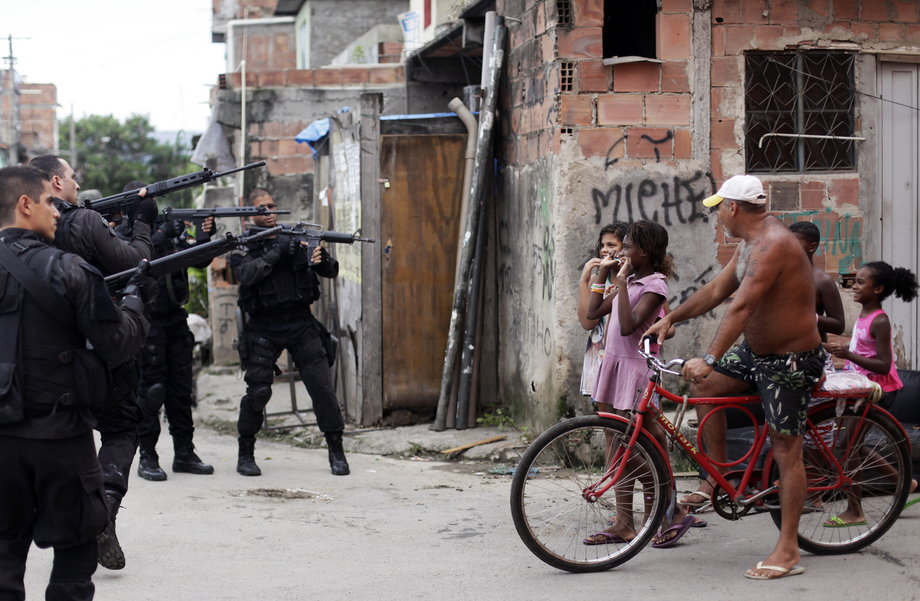 Residents react as policemen take position during an operation in the Maré slums complex in Rio de Janeiro, March 26, 2014. Brazil deployed federal troops to Rio to help quell violent crime following attacks by drug traffickers on police posts in three slums on the north side of the city.