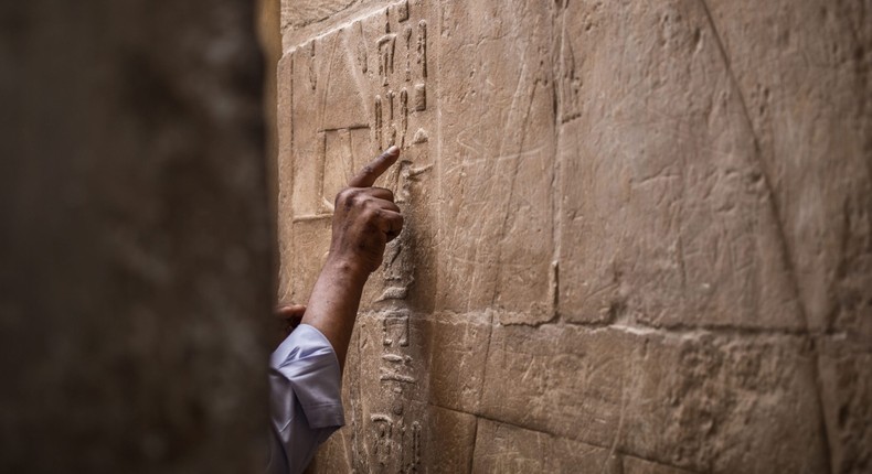 A Egyptian man points at hieroglyphs in the mastaba tomb of Seshem Nefer Theti at the Giza Pyramid complex.