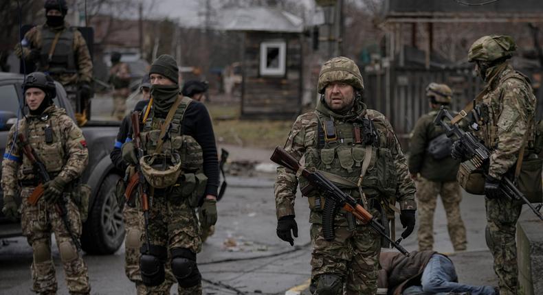 Ukrainian servicemen stand while checking bodies of civilians for booby traps, in the formerly Russian-occupied Kyiv suburb of Bucha, Ukraine, Saturday, April 2, 2022.