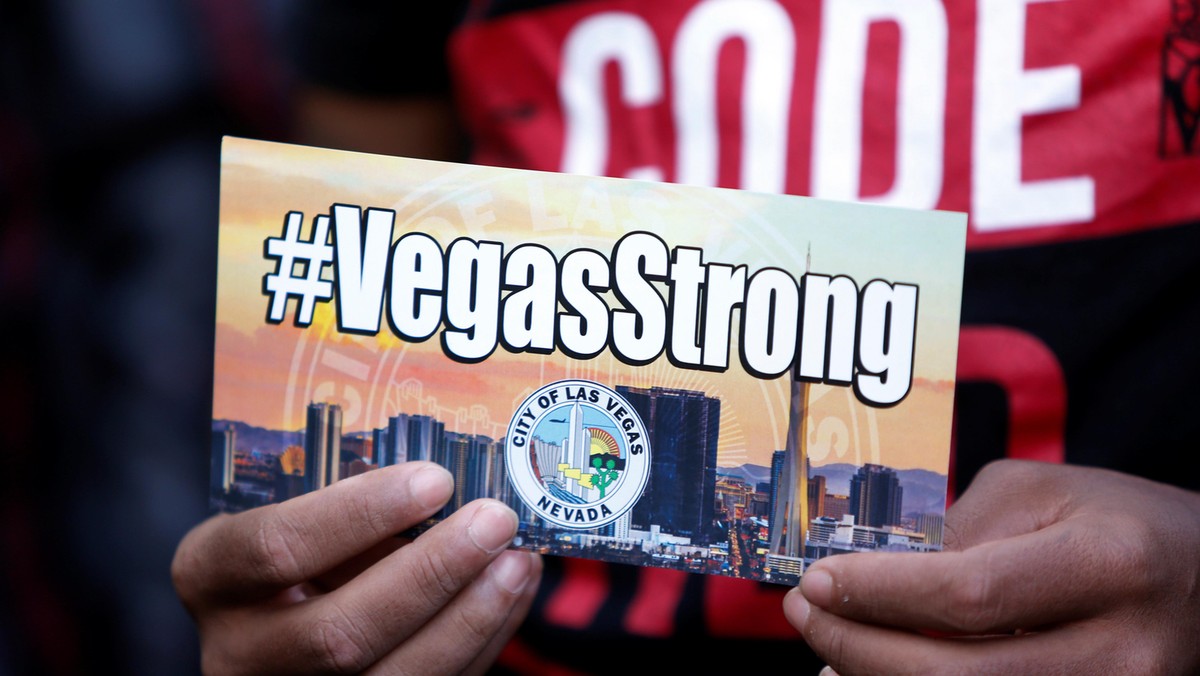 A man holds a sign during a prayer vigil in honor of those affected by the shooting in Las Vegas