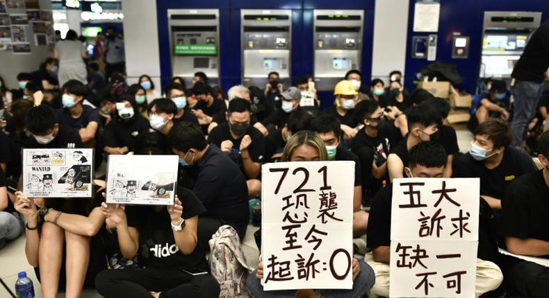 Protesters hold placards during a sit-in at Yuen Long MTR station in Hong Kong