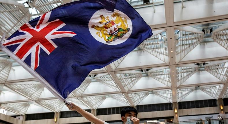 A protester waves the former British colonial Hong Kong flag at arally in a shopping mall. A new Chinese security law imposed on the city is causing fresh tension between London and Beijing