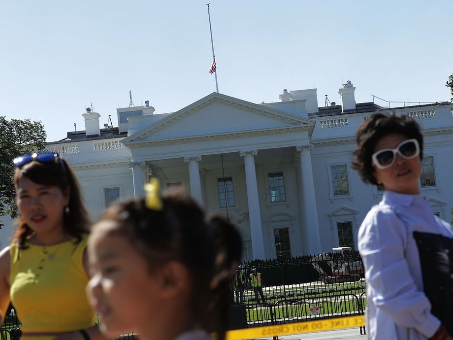 Tourists pose for photographs as the U.S. flag flies at half-staff over the White House October 2, 2017 in Washington, DC.