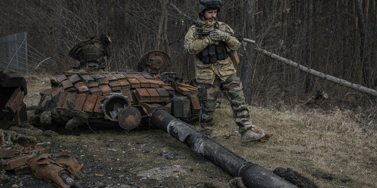 Ukraina. Ukraiński żołnierz obok wraku rosyjskiego czołgu