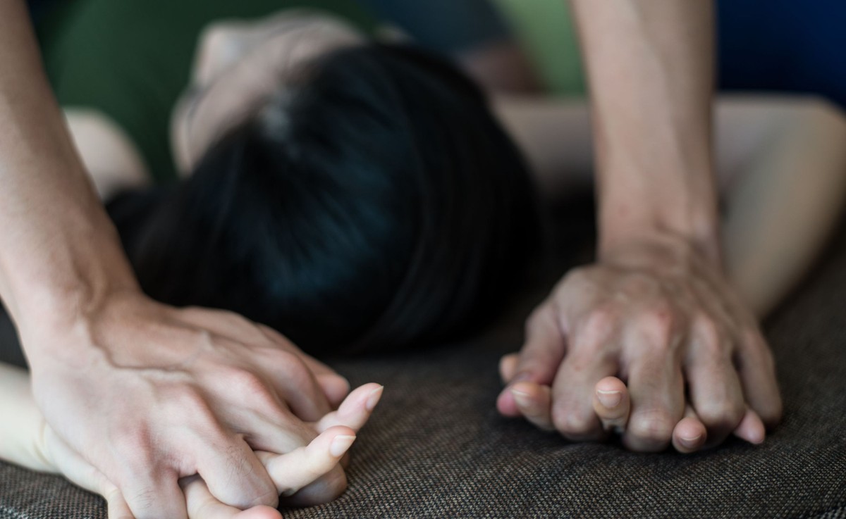 Mężczyzna trzyma dłonie kobiety, leżąc na niej