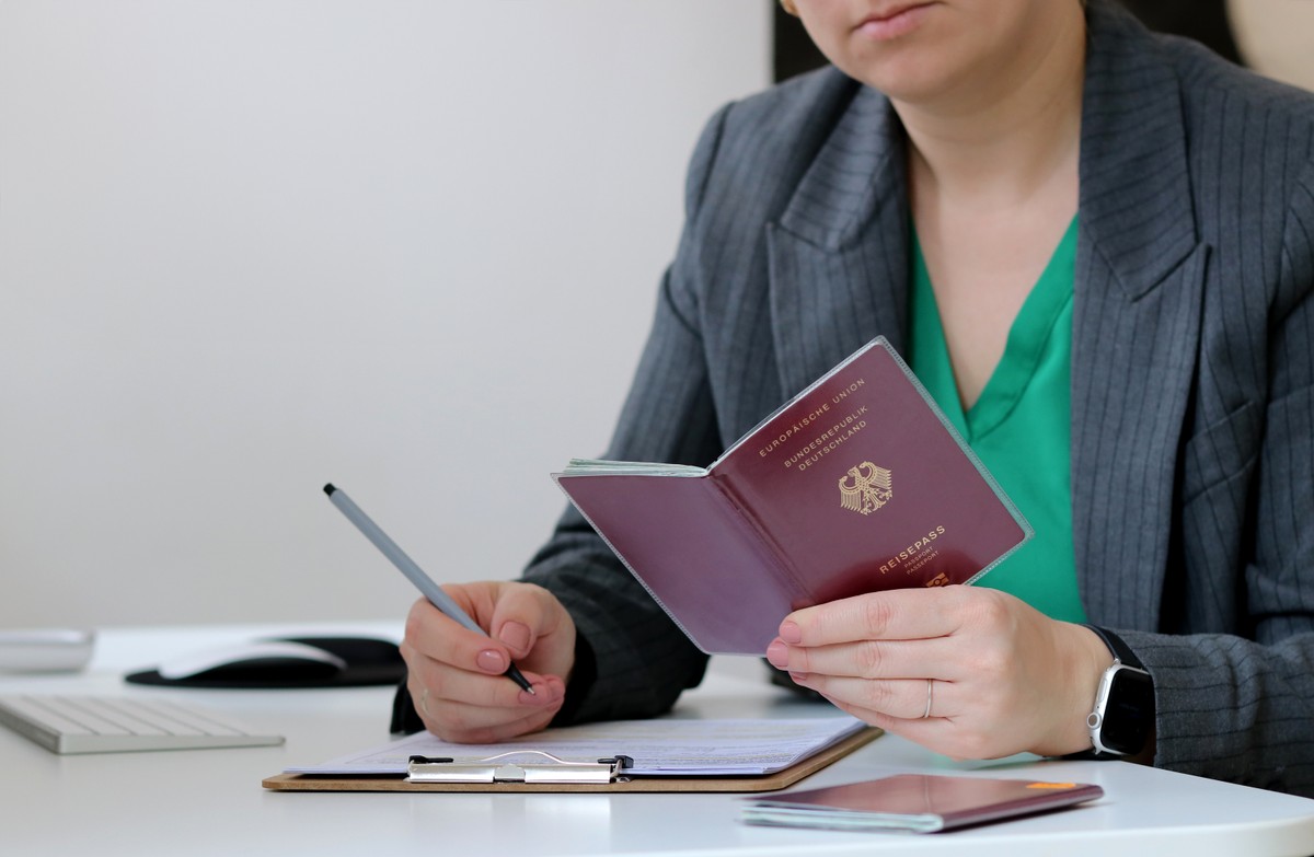 Kobieta wypełnia dokumenty, trzymając w dłoni paszport