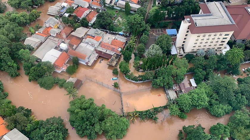 A man looks at a car damaged by the flood at a residential area in Bekasi