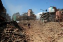 Member of Nepalese police personnel walks amidst the rubble of collapsed buildings, in the aftermath of Saturday's earthquake in Kathmandu, Nepal