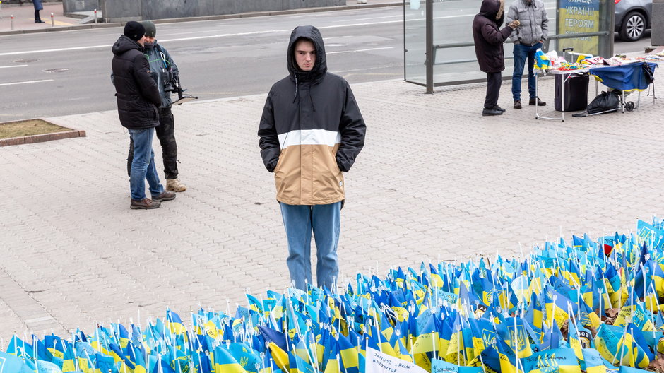 Młody Ukrainiec stoi przy miejscu upamiętniającym poległych żołnierzy w Kijowie, luty 2023 r.