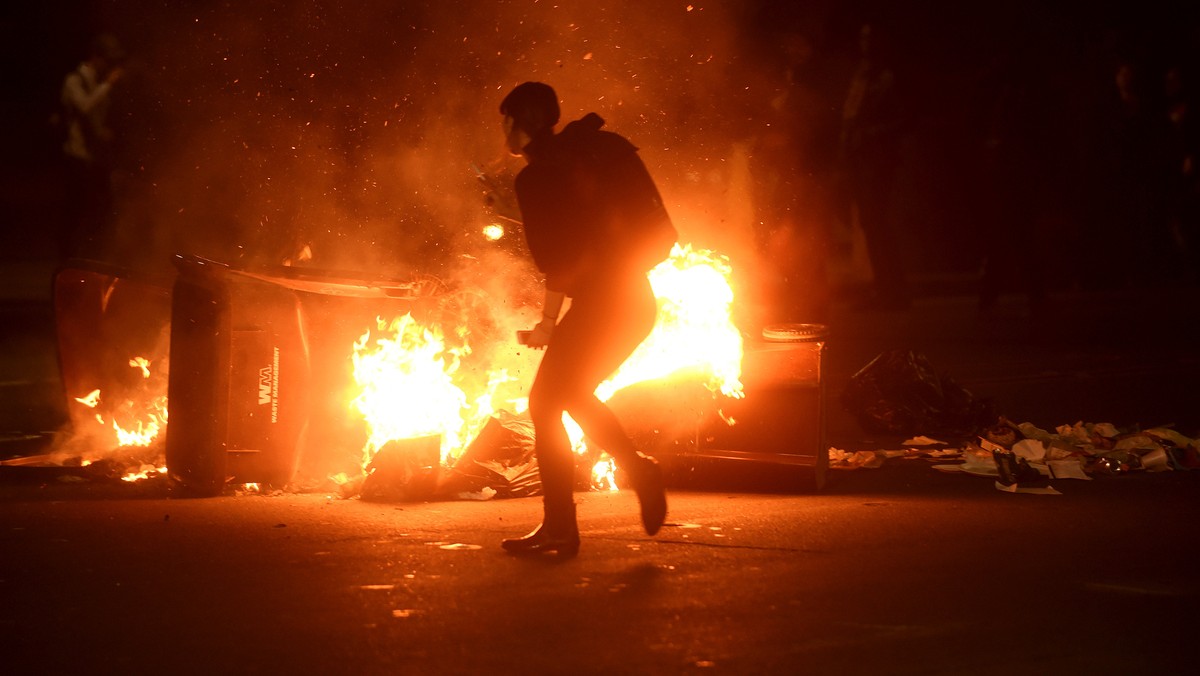 A woman passes burning garbage during a demonstration in Oakland, California, U.S. following the election of Donald Trump