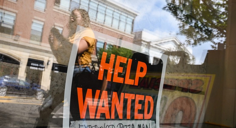 A Help Wanted sign hangs in the window of Gino's Pizza on Main Street in Patchogue, New York on August 24, 2021.