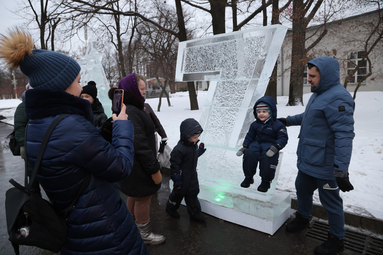 Kobieta robiąca zdjęcie dzieciom w pobliżu gigantycznej litery "Z", zainstalowanej przez władze Moskwy jako symbol poparcia dla inwazji na Ukrainę, 15 stycznia 2023 r.