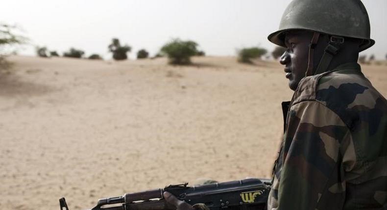 A Malian soldier, holding an AK-47 rifle, rides in a pick-up truck during a military escort outside Timbuktu, Mali, July 27, 2013.   REUTERS/Joe Penney