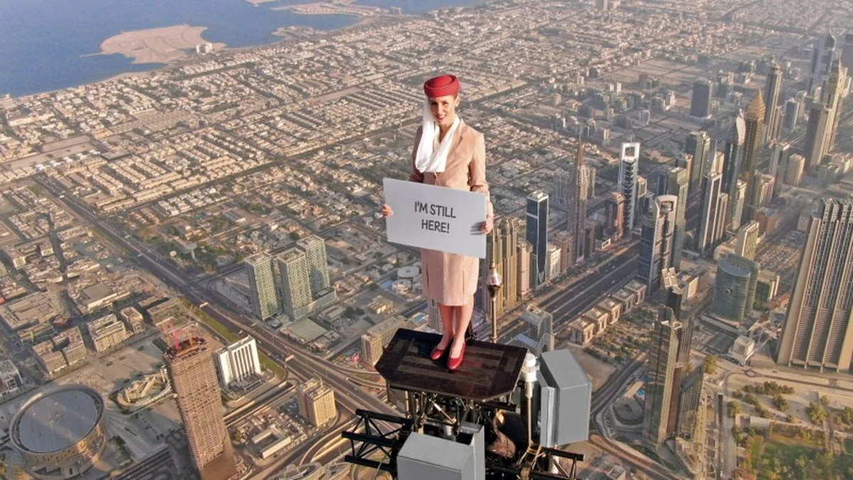 Stewardesa stanęła na najwyższym budynku świata. Za nią przeleciał samolot