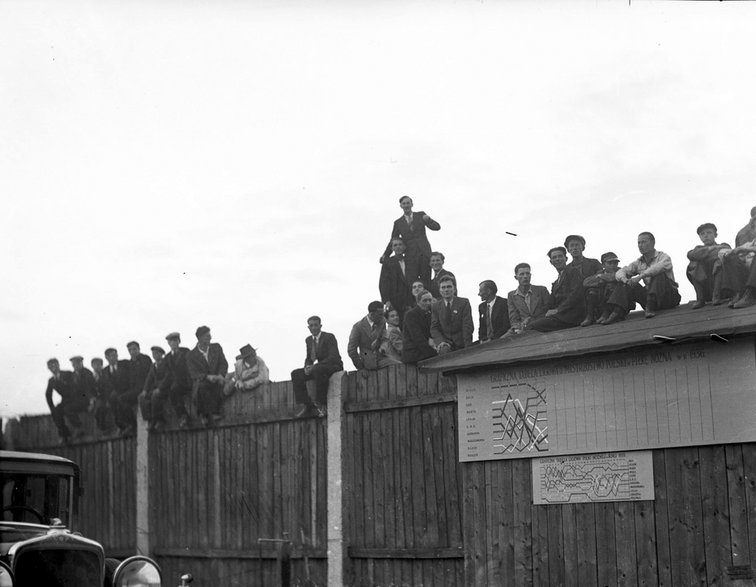 Siedzący na płocie kibice oglądają mecz Wisła – Chelsea, który rozegrano w 1936 r. Źródło: Narodowe Archiwum Cyfrowe.