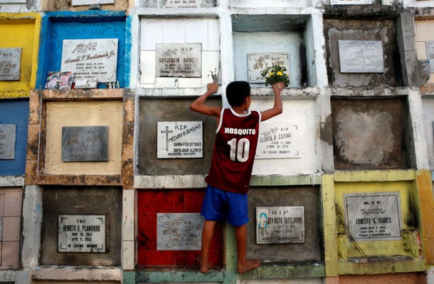 A resident places a flower bouquet in front of a tomb ahead of the commemoration of All Saints day i