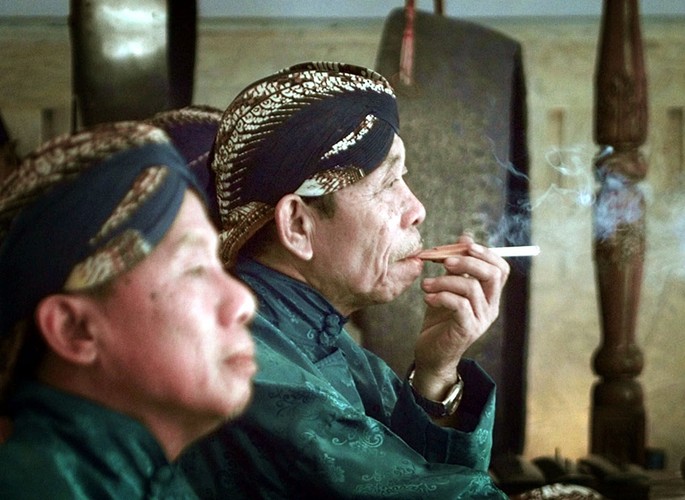 Indonezyjscy muzycy relaksują się, paląc tradycyjne papierosy zwane kretek na ulicy w Dżakarcie