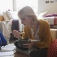 Female college student eating and studying on floor in dorm room