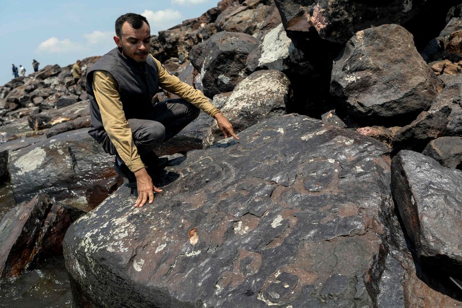 Archaeologist Jaime de Oliveira shows a face carved in stone at the Lajes archaeological site on October 21.