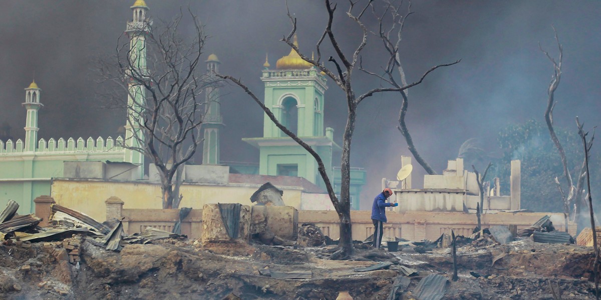 A man stands in front of a mosque as it burns in Meikhtila, Myanmar, on March 21, 2013.