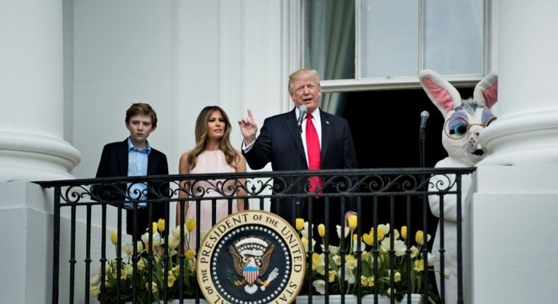 US President Donald Trump, alongside son Barron Trump (L) and US First Lady Melania Trump (2L), speaks during the Easter Egg Roll on the South Lawn of the White House in Washington, DC on April 17, 2017