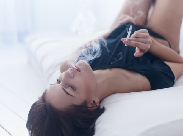 Kobieta w łóżku pali papierosa