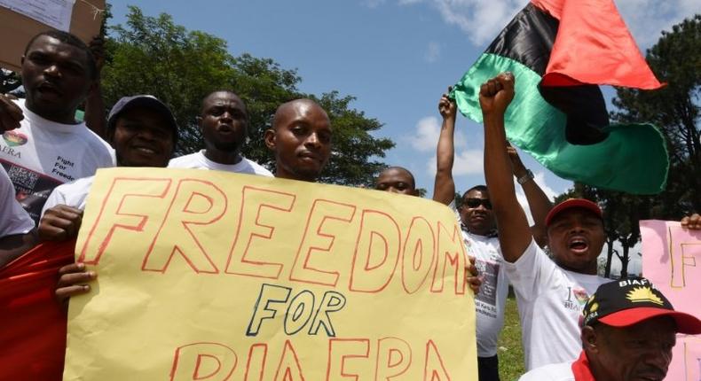 Demonstrators from the Indigenous People of Biafra (IPOB) group wave flags and hold a sign reading Freedom for Biafra during a protest in Abidjan on September 23, 2016 calling for the release of pro-Biafra leader Nnamdi Kanu