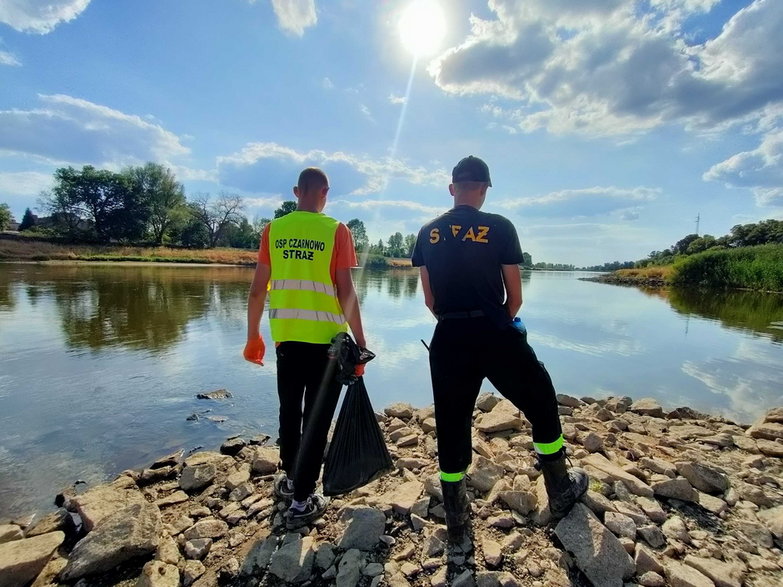 Członkowie Społecznej Straży Rybackiej pracują przy brzegu rzeki