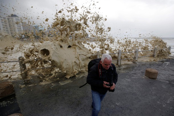 A man runs from sea spray as storms hit Cape Town