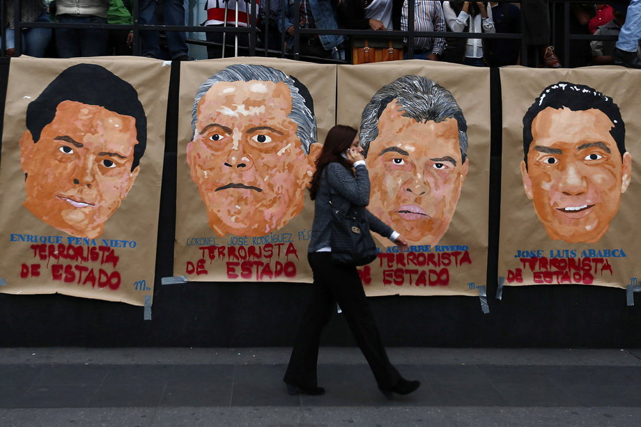 A woman walks past posters during a demonstration to demand for justice for the 43 missing Ayotzinapa students, in Mexico City, January 26, 2015. The posters read, left to right: "Enrique Pena Nieto. Terrorist of state; Coronel Jose Rodriguez Perez, Terrorist of state; Angel Aguirre Rivero, Terrorist of state; Jose Luis Abarca, Terrorist of state."