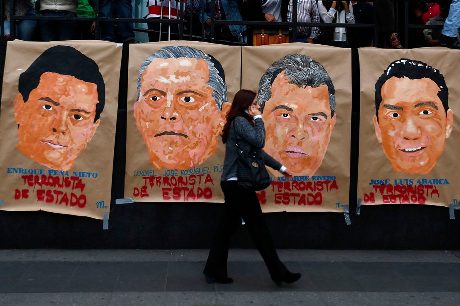 A woman walks past posters during a demonstration to demand for justice for the 43 missing Ayotzinapa students, in Mexico City, January 26, 2015. The posters read, left to right: "Enrique Pena Nieto. Terrorist of state; Coronel Jose Rodriguez Perez, Terrorist of state; Angel Aguirre Rivero, Terrorist of state; Jose Luis Abarca, Terrorist of state."