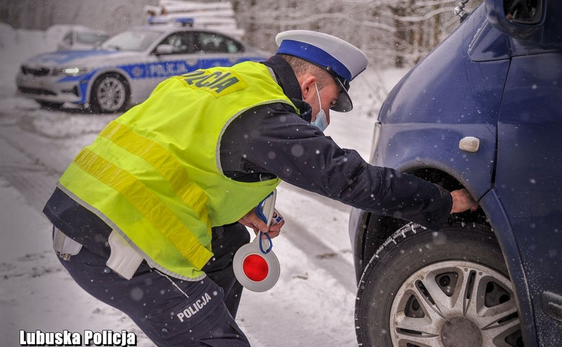 Policjant kontroluje stan opon zimowych